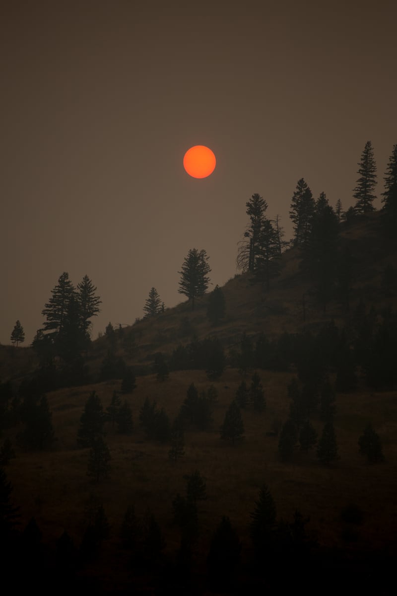 A forest-fire-red sun burns through smoke over the ridge country toward Pemberton, photographed after a Whistler yoga retreat.