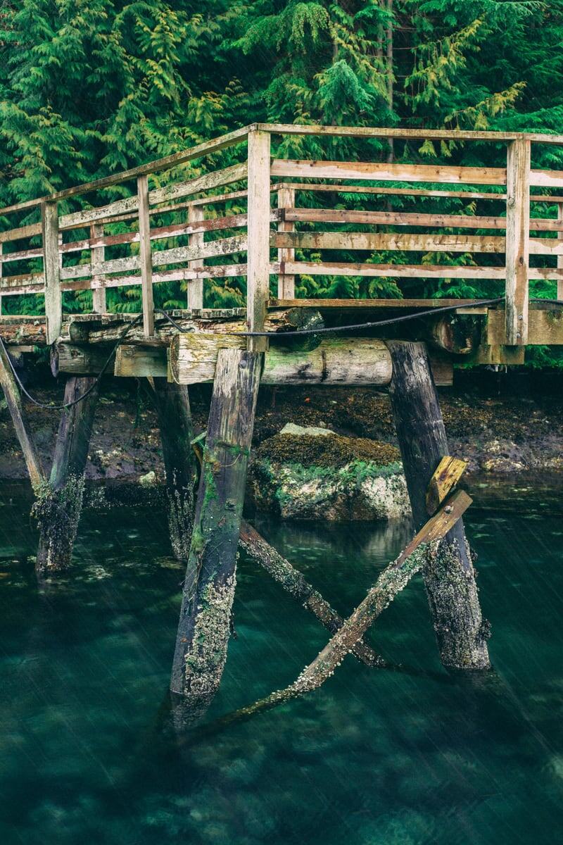 A weathered green dock and pilings hold over deep Sunshine Coast water.