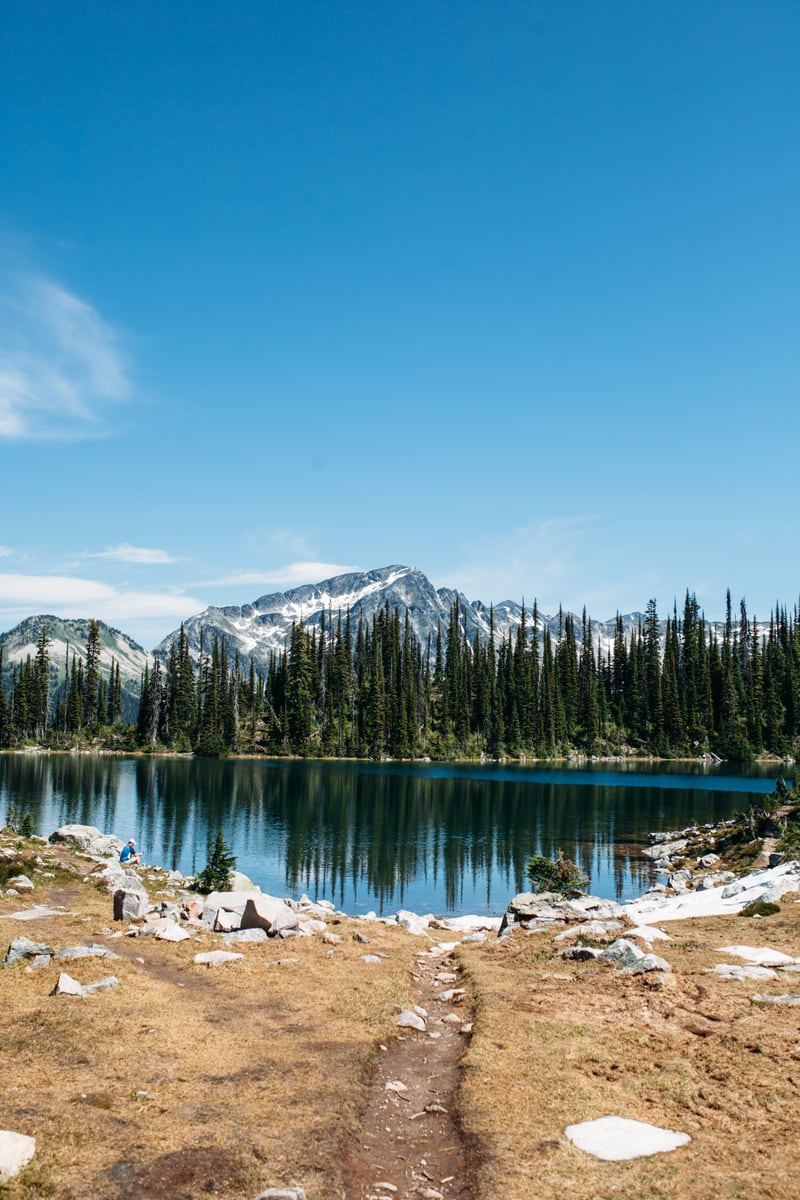 A bright alpine lake and melting snow path in Mount Revelstoke National Park.