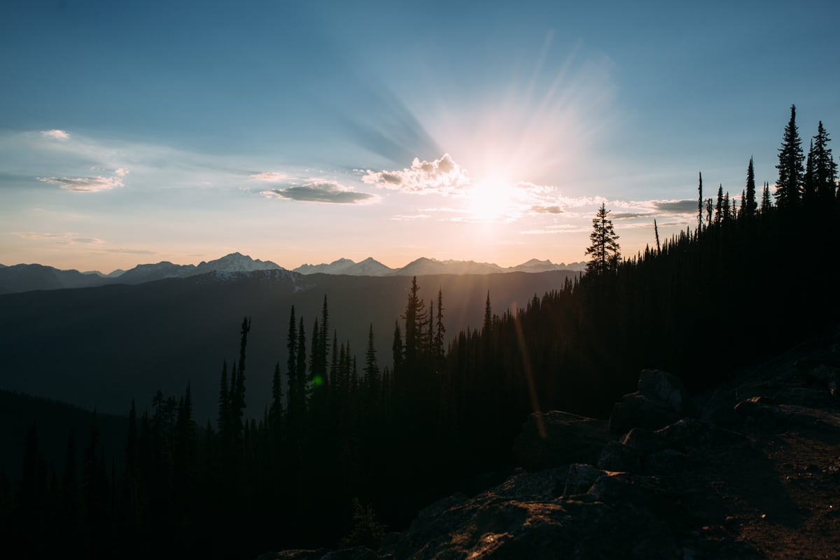 Sunlight breaks over layered ridges and dark trees in Mount Revelstoke.