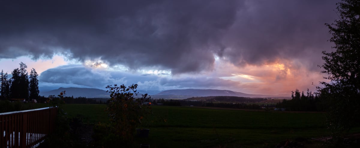 A wide storm-lit field and valley view near Armstrong and Spallumcheen.