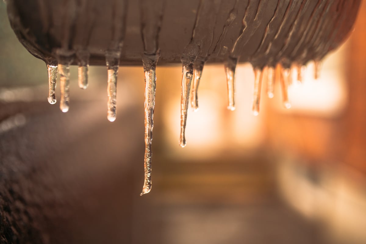Icicles catch warm light beneath a roofline in winter.