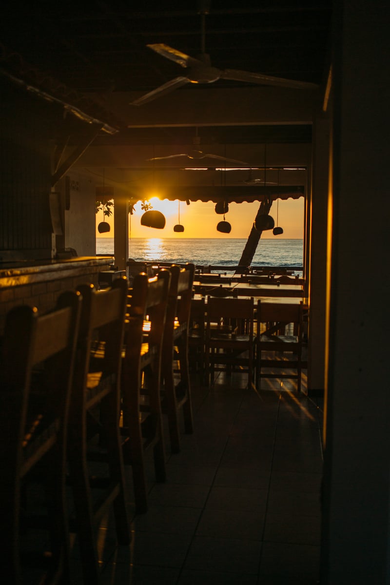 A warm interior frame looking toward a Costa Rica sunset beyond the rail.