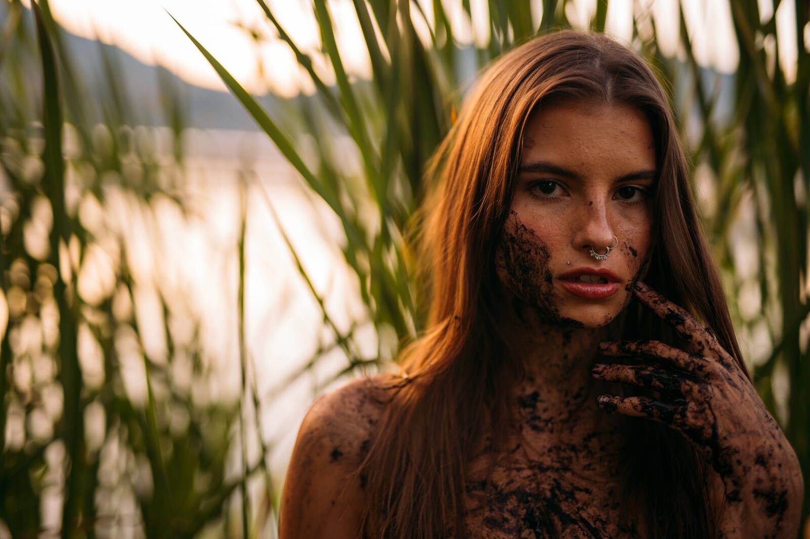 Mo in the Reeds story frame 8: Green shadow, tall grass, body paint and a charged quiet that stays grounded in portrait atmosphere.