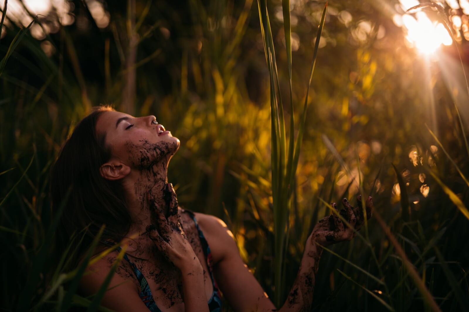 Mo in the Reeds story frame 5: Green shadow, tall grass, body paint and a charged quiet that stays grounded in portrait atmosphere.