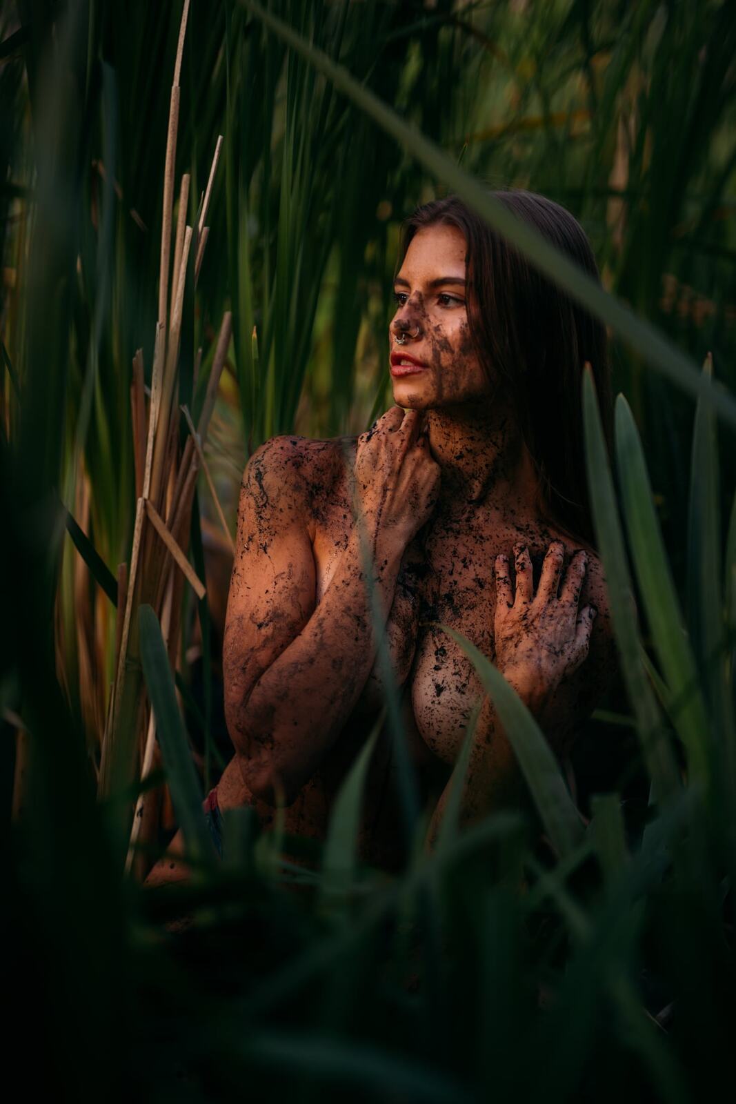 Mo in the Reeds story frame 14: Green shadow, tall grass, body paint and a charged quiet that stays grounded in portrait atmosphere.