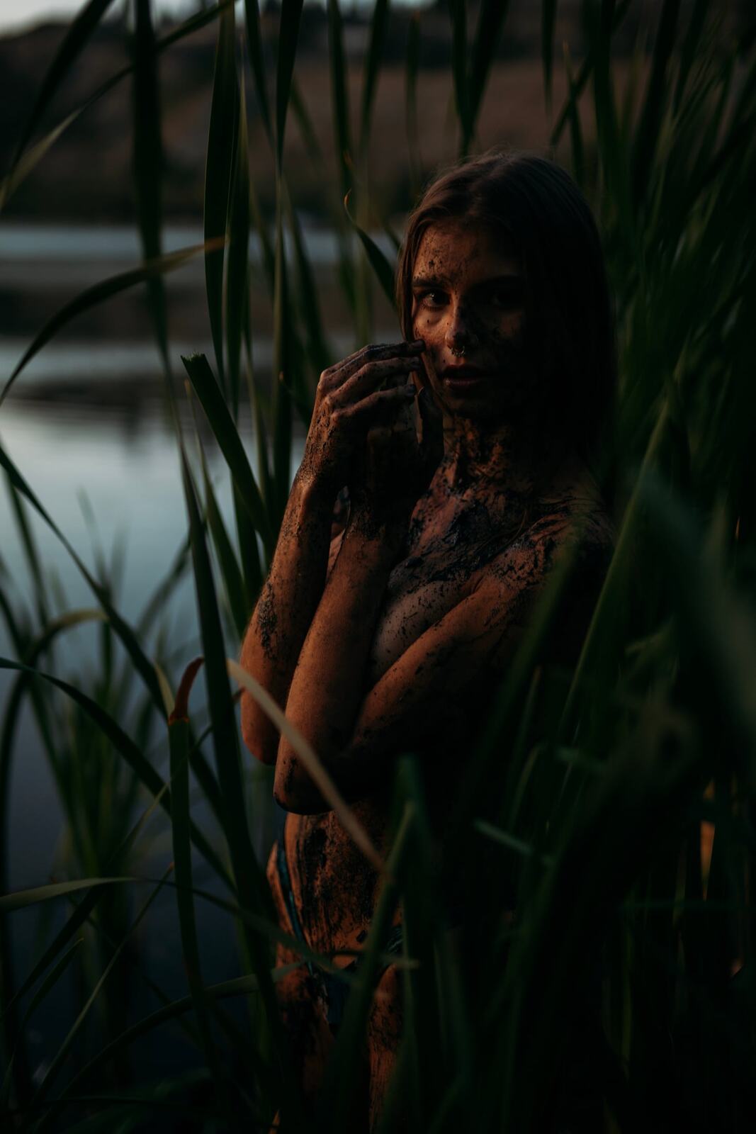 Mo in the Reeds story frame 20: Green shadow, tall grass, body paint and a charged quiet that stays grounded in portrait atmosphere.
