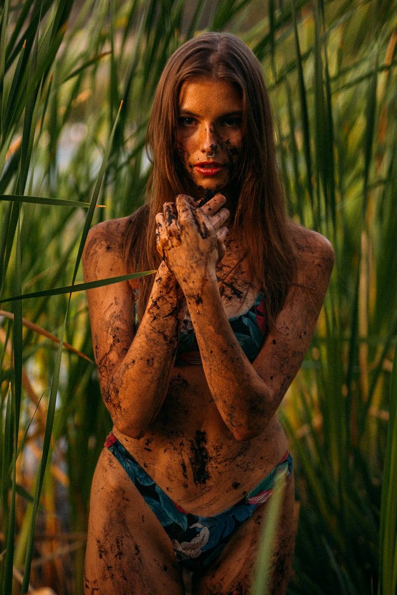 Mo in the Reeds story frame 9: Green shadow, tall grass, body paint and a charged quiet that stays grounded in portrait atmosphere.
