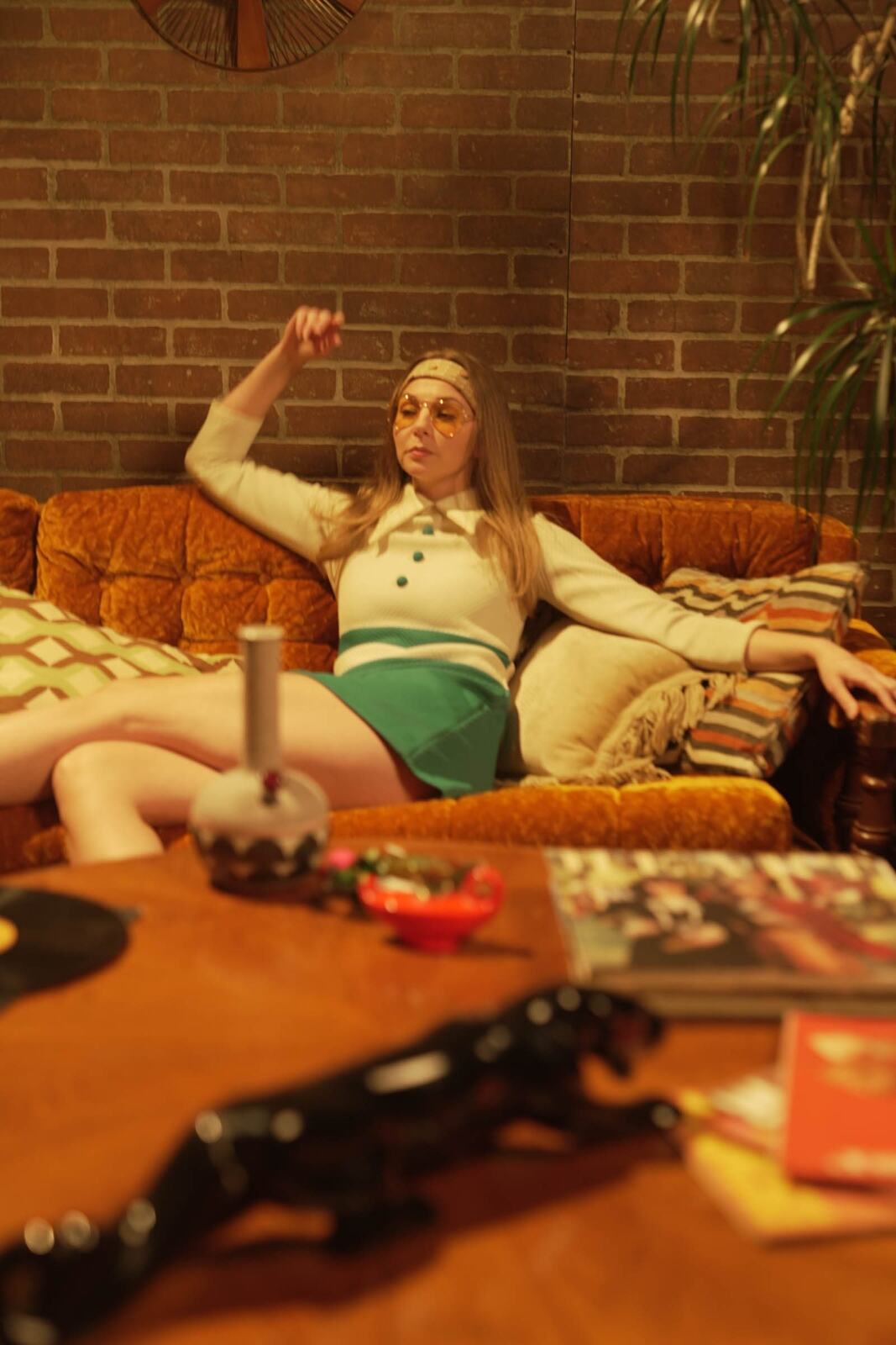 Angela in the 70s Lounge portraits story frame 7: A warm 70s lounge portrait story with yellow glasses, retro styling, couch texture and a softer studio mood.