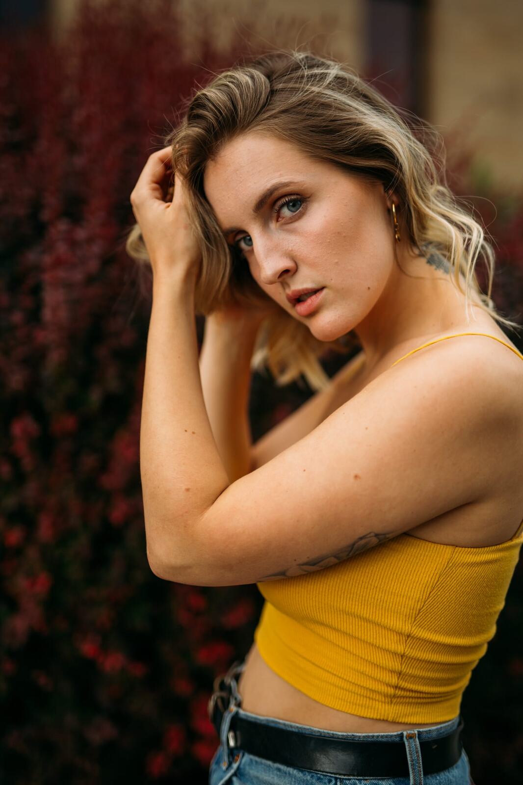 Brittany in Yellow and Blue portraits story frame 4: A two-look Kelowna portrait story for Brittany, led by the yellow styling and dark green texture, then moving into blue lakeside frames and a soft rainbow-bokeh finish.