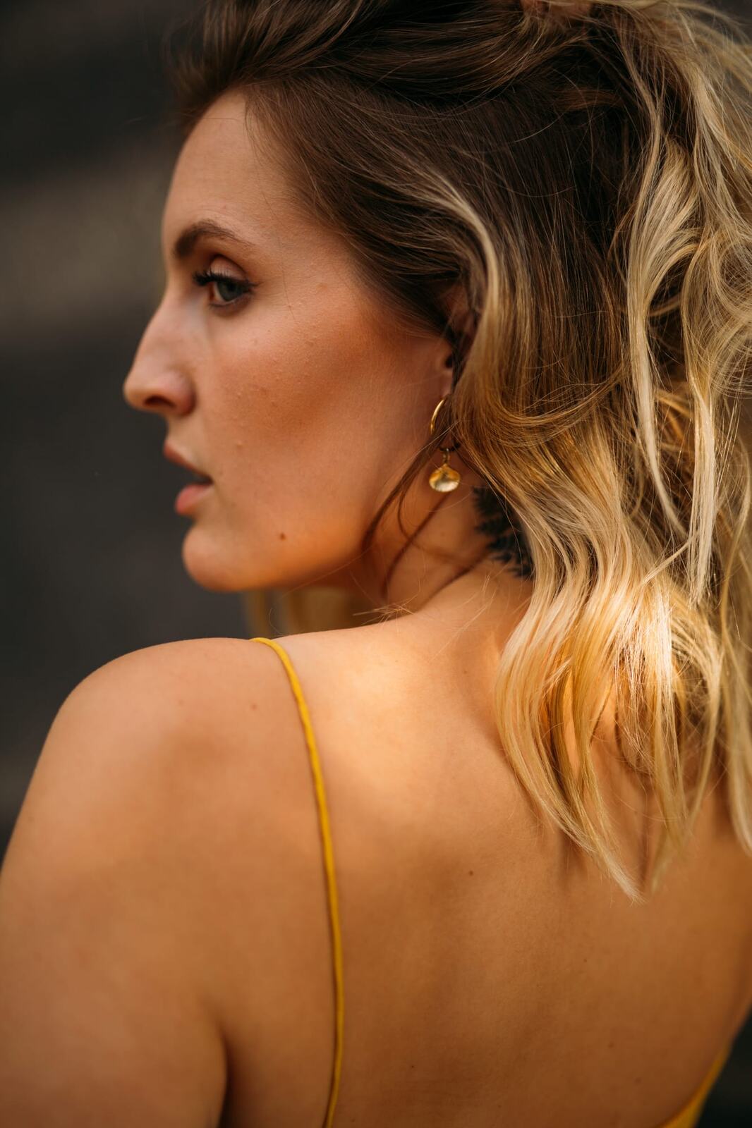 Brittany in Yellow and Blue portraits story frame 9: A two-look Kelowna portrait story for Brittany, led by the yellow styling and dark green texture, then moving into blue lakeside frames and a soft rainbow-bokeh finish.