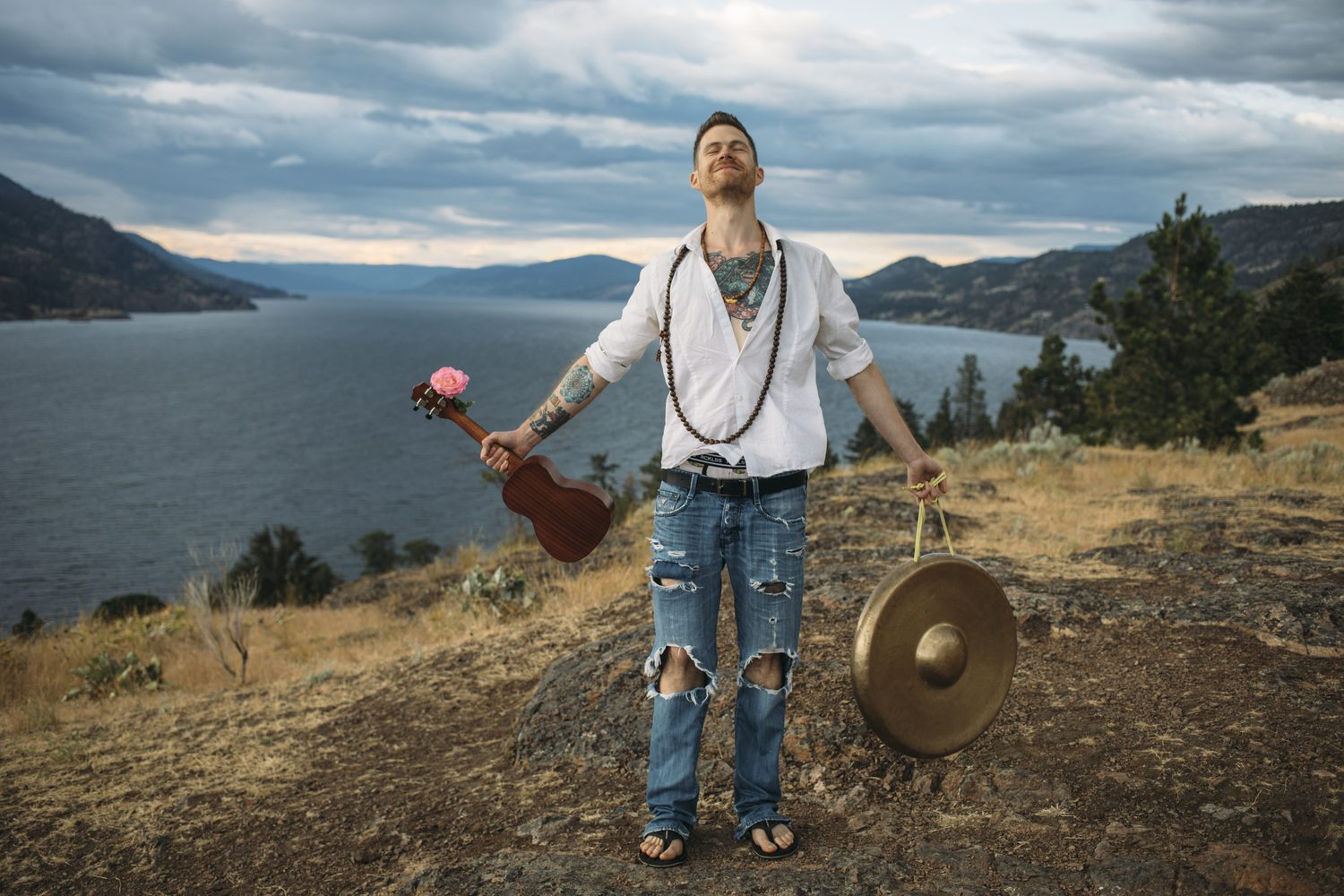 Jacob opening his arms while holding instruments above the lake.