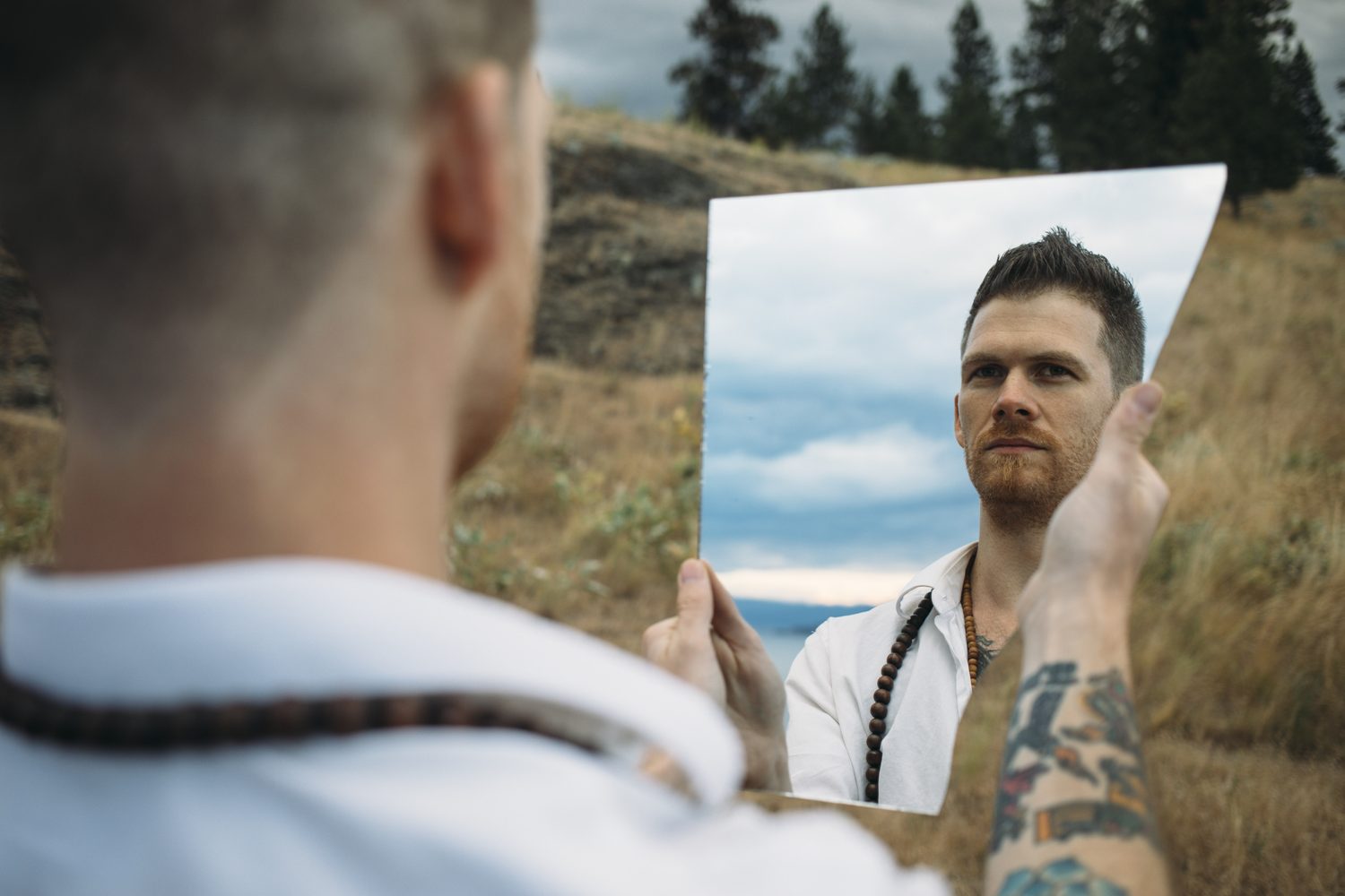 Jacob reflected in a round mirror held against the landscape.