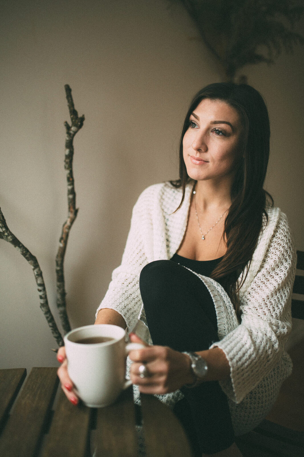 Jasmin by the Window portrait story frame 3: Window-light portraits with Jasmin beside a small table, tea and winter greenery in Kelowna, British Columbia.