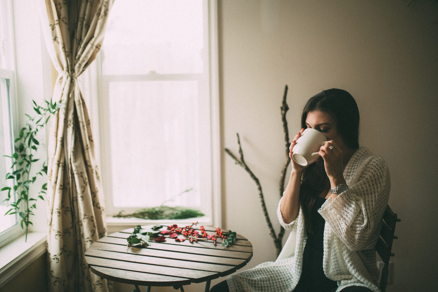 Jasmin by the Window portrait story frame 13: Window-light portraits with Jasmin beside a small table, tea and winter greenery in Kelowna, British Columbia.
