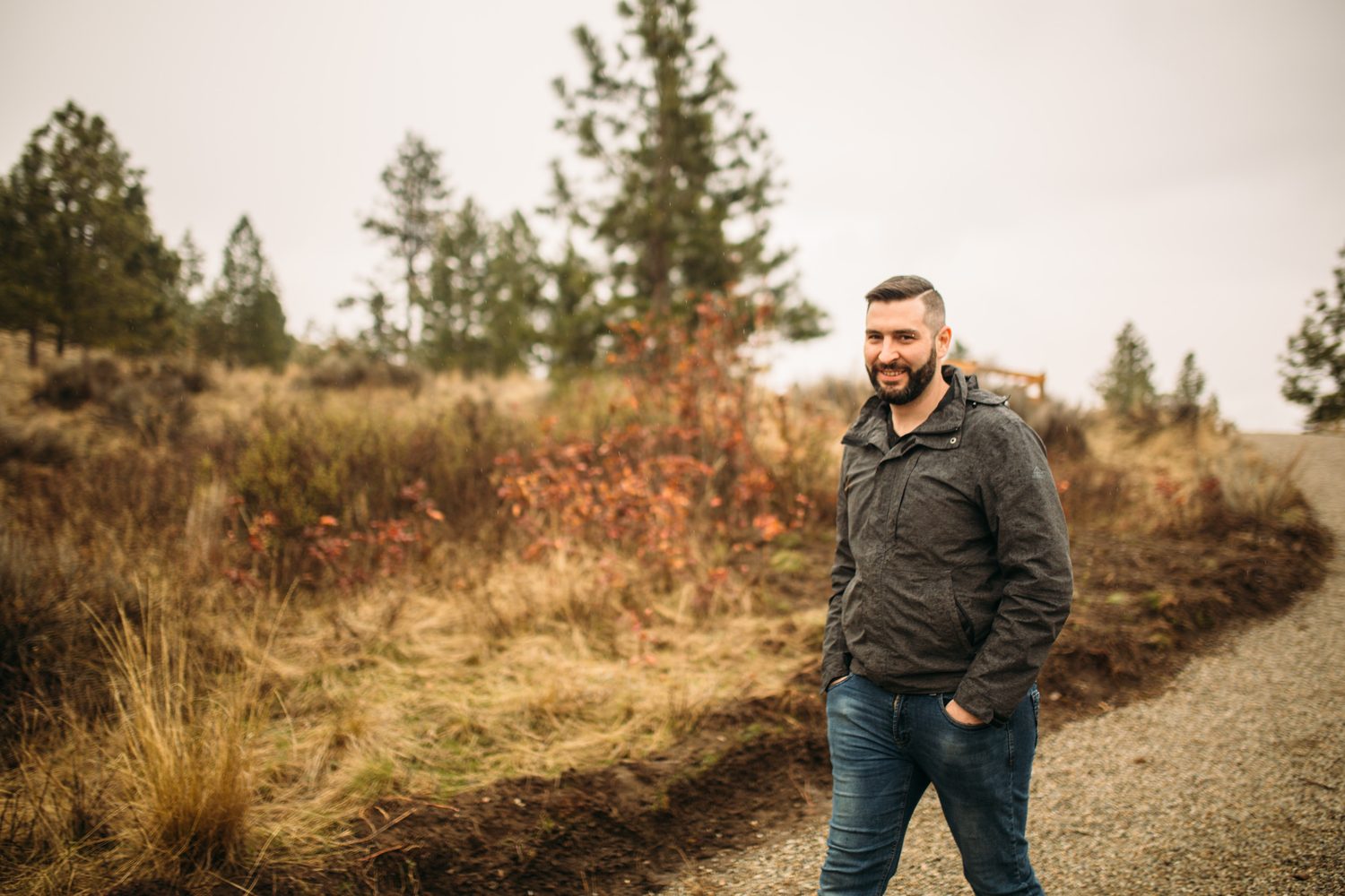 Vertical portrait of Jeremy seated among tall grass at Knox Mountain.