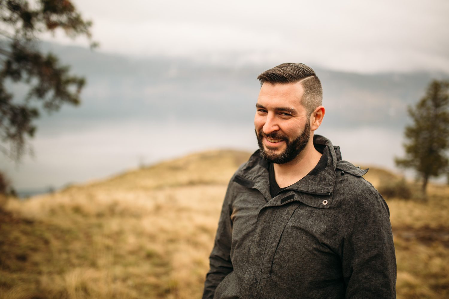 Jeremy standing in warm hillside light in a dark blazer for Optimize Organics.