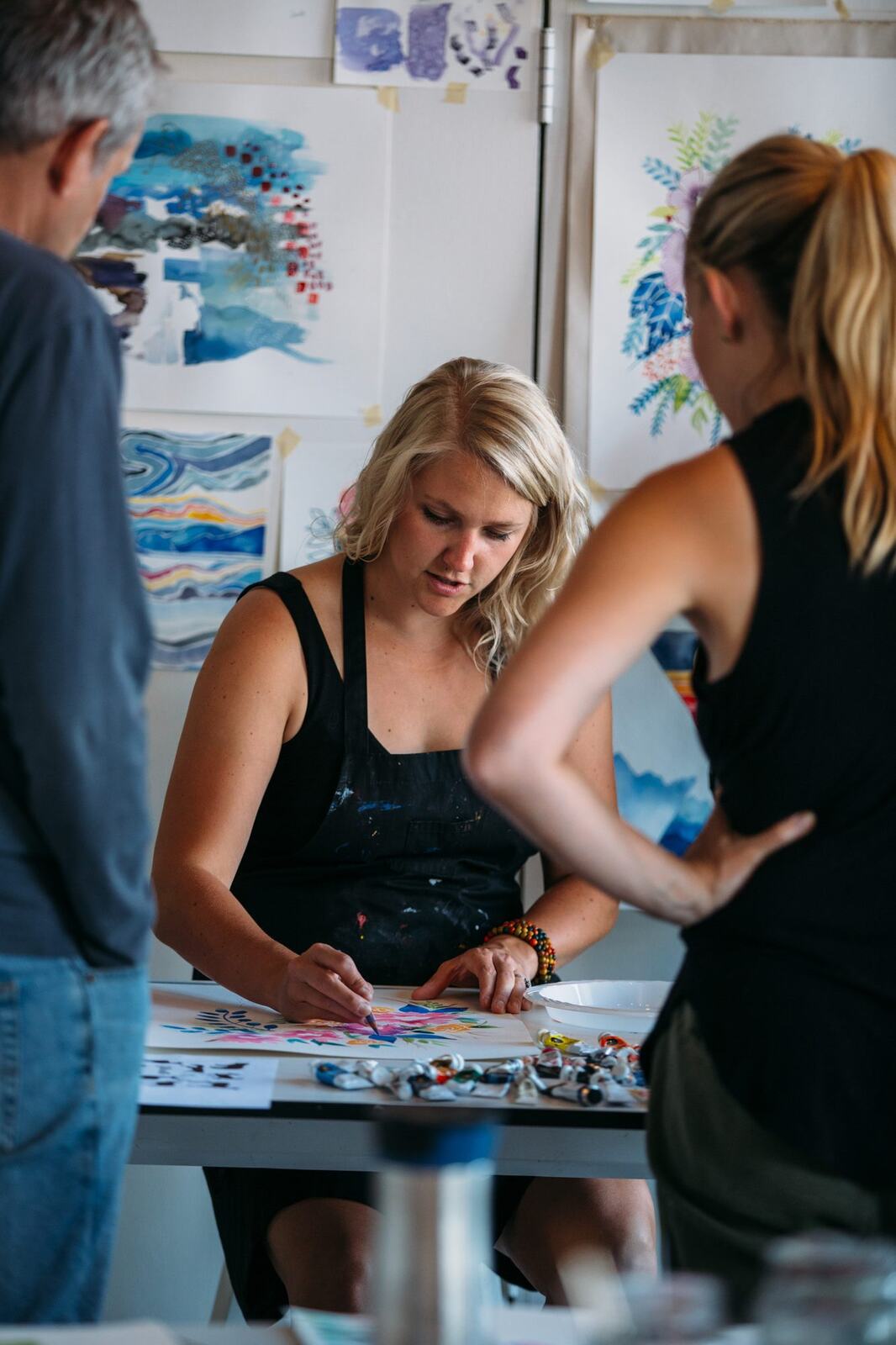Workshop discussion in front of watercolour examples on the studio wall.