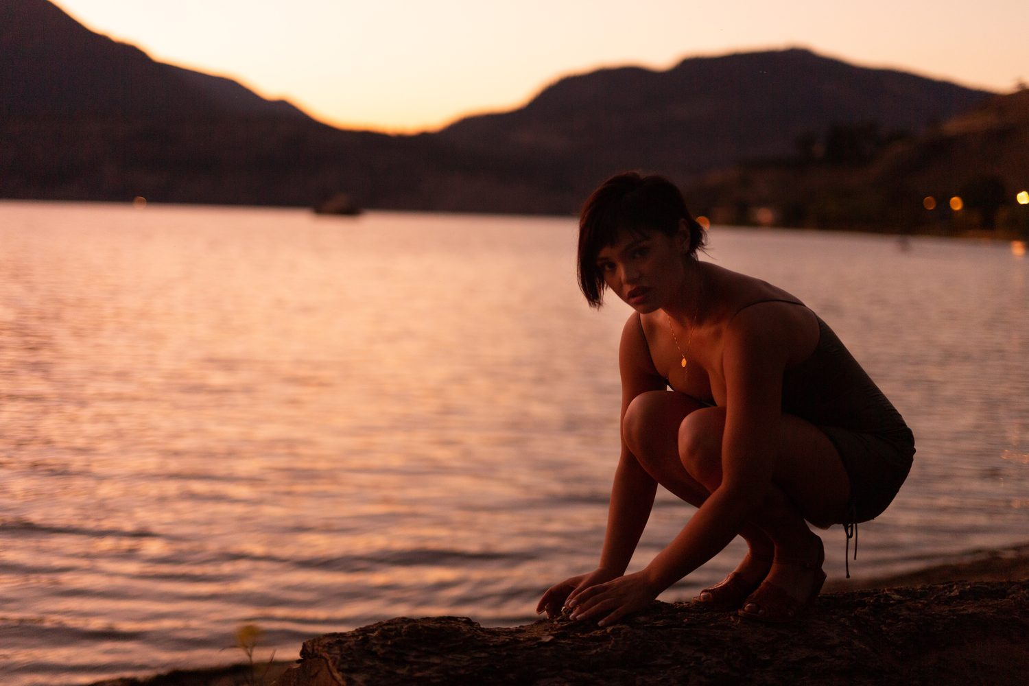 Lucy at the Water’s Edge portraits story frame 5: Lucy at the water’s edge as sunset slips into moonlight, moving from the shoreline and rocks to quiet close portraits and a warm-lit garden after dark. Photographed in Kelowna, BC.