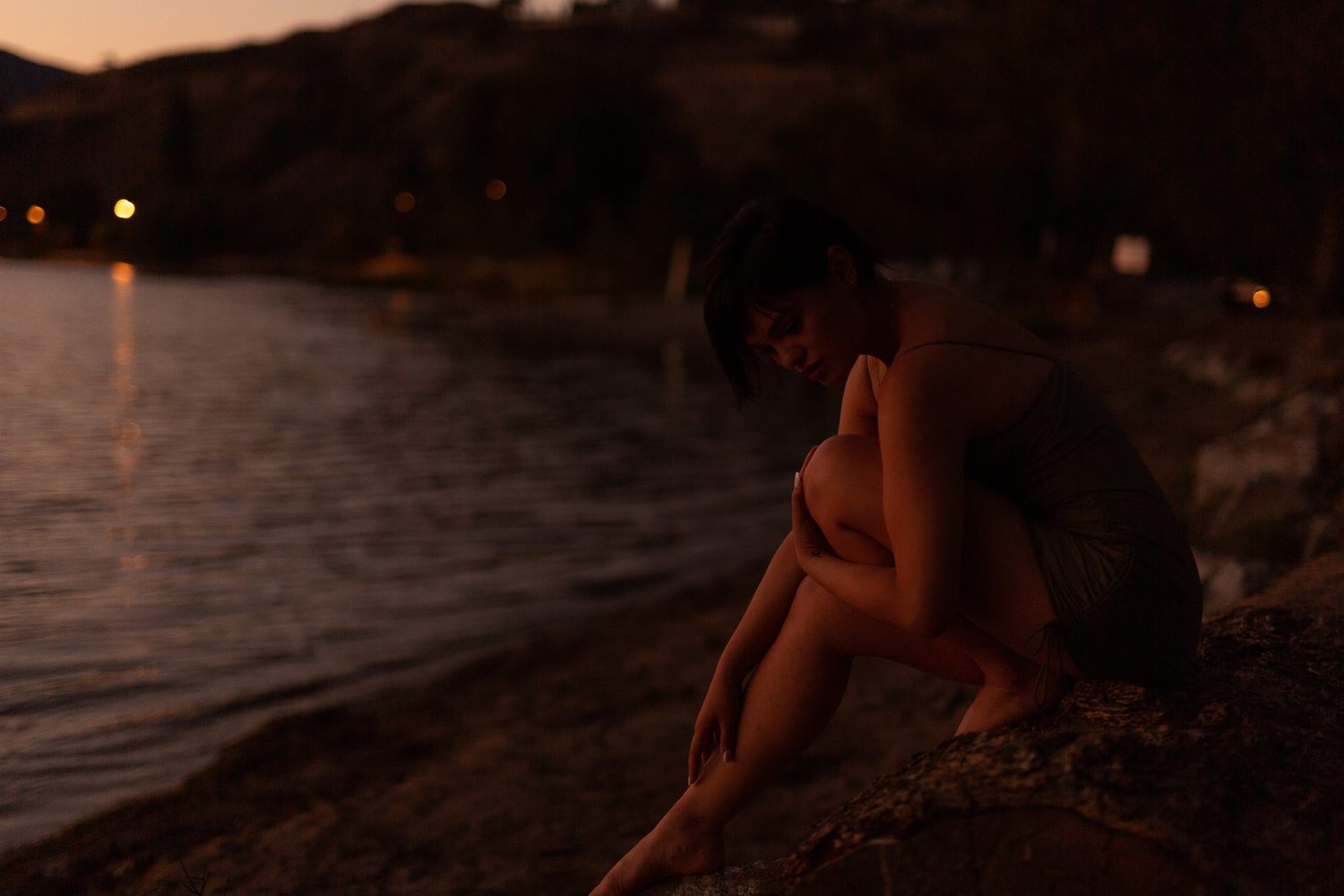 Lucy at the Water’s Edge portraits story frame 6: Lucy at the water’s edge as sunset slips into moonlight, moving from the shoreline and rocks to quiet close portraits and a warm-lit garden after dark. Photographed in Kelowna, BC.