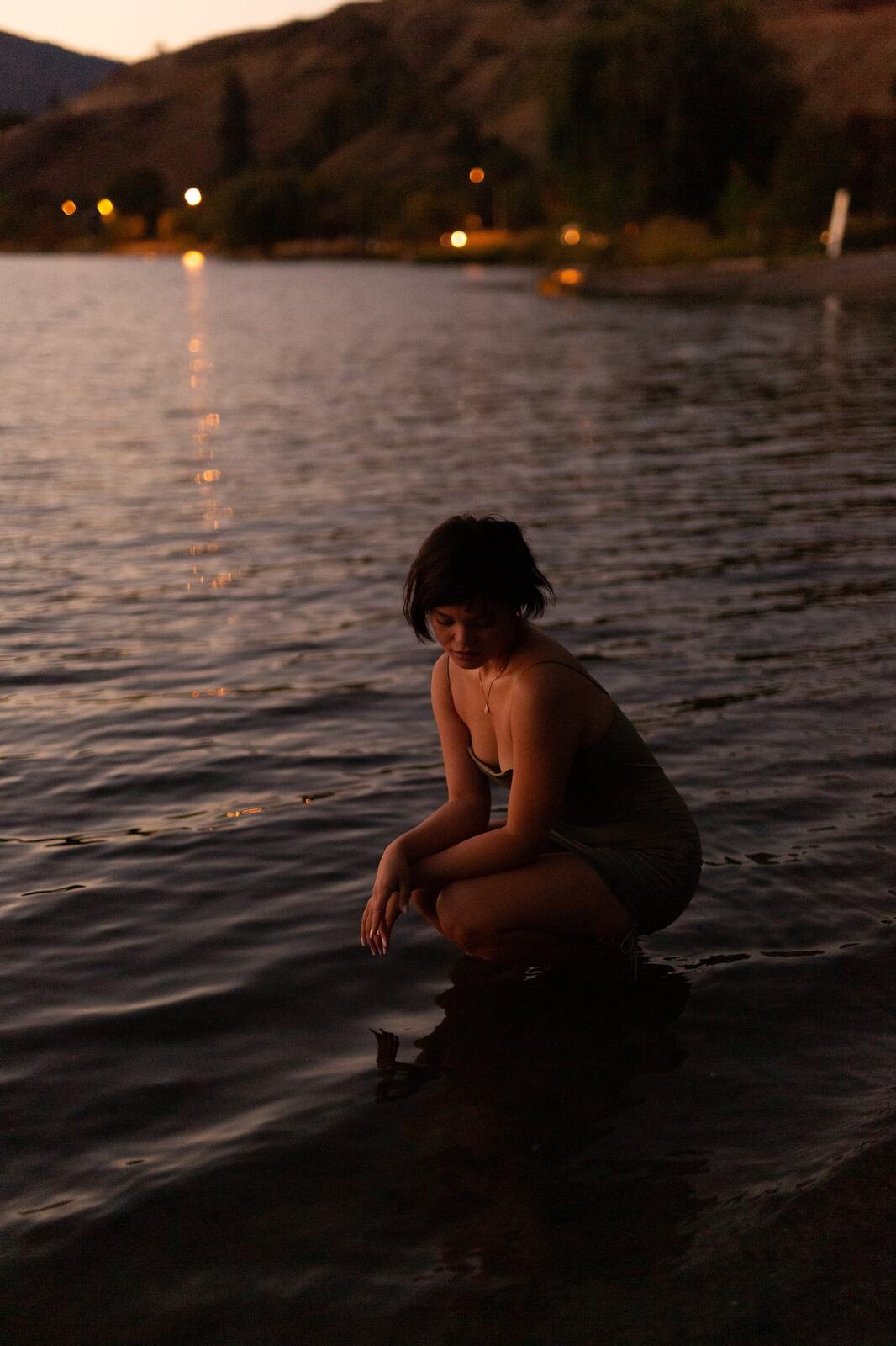 Lucy at the Water’s Edge portraits story frame 12: Lucy at the water’s edge as sunset slips into moonlight, moving from the shoreline and rocks to quiet close portraits and a warm-lit garden after dark. Photographed in Kelowna, BC.