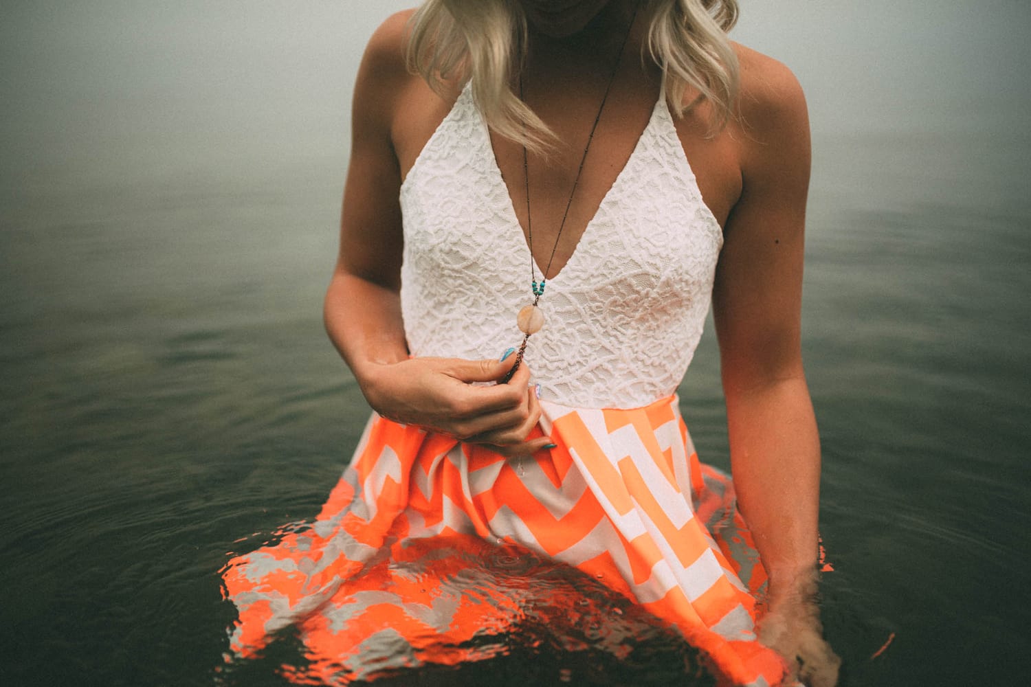 Megan Shallow portraits story frame 4: A fog-soft Kelowna lake portrait session for Megan Shallow, with water, orange dress movement, close body-language frames and quiet birds cutting through the mist.