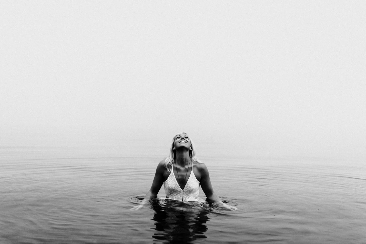 Megan Shallow portraits story frame 6: A fog-soft Kelowna lake portrait session for Megan Shallow, with water, orange dress movement, close body-language frames and quiet birds cutting through the mist.