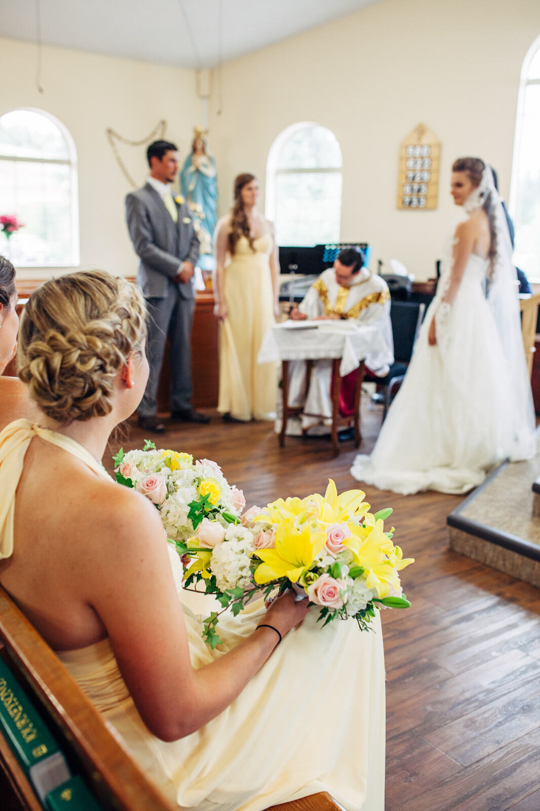 A guest holding a yellow bouquet during the ceremony
