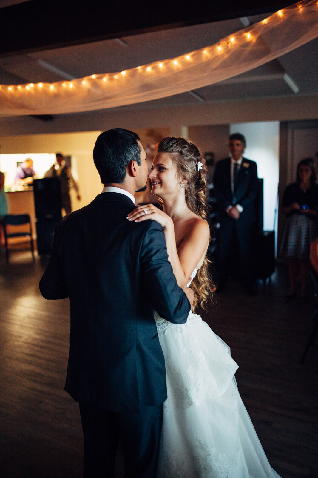 Mel and Blaise dancing beneath warm reception lights