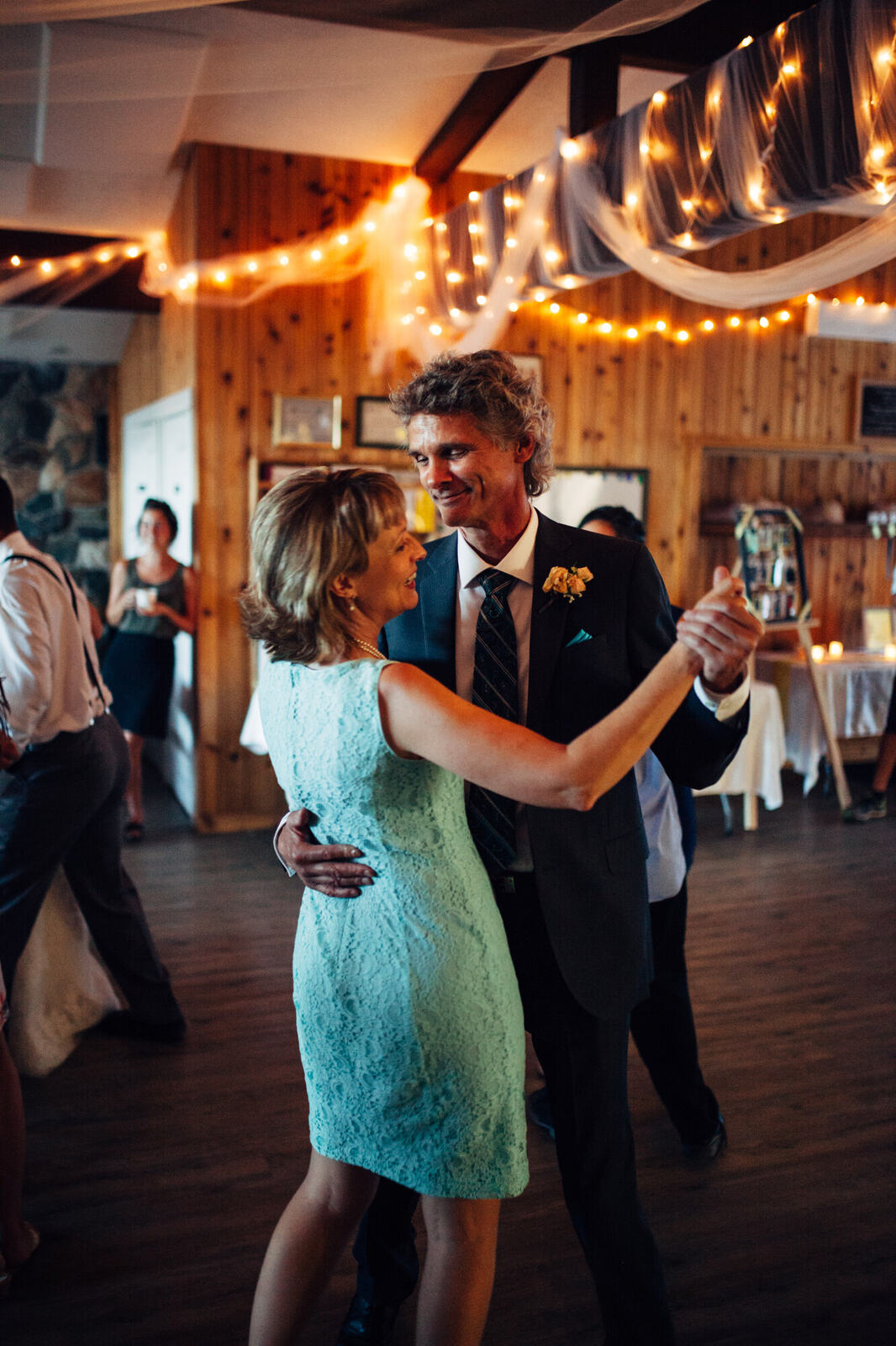 Wedding guests dancing beneath string lights
