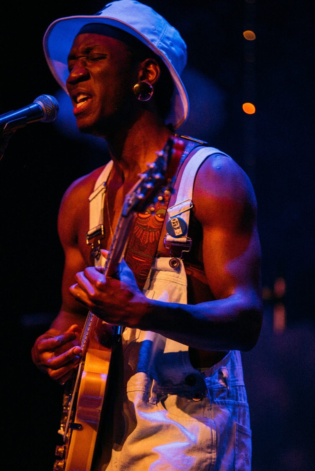 Guitarist in a striped shirt performing against warm smoke and shadow.