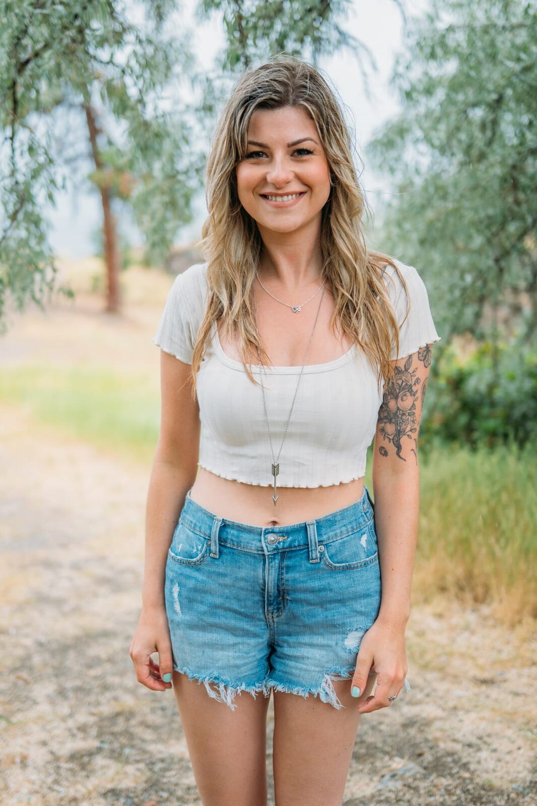 Sophia by the Lake portraits story frame 6: A multi-outfit Okanagan location session with water, trees, shoreline, denim and red swimwear woven into a summer portrait story.