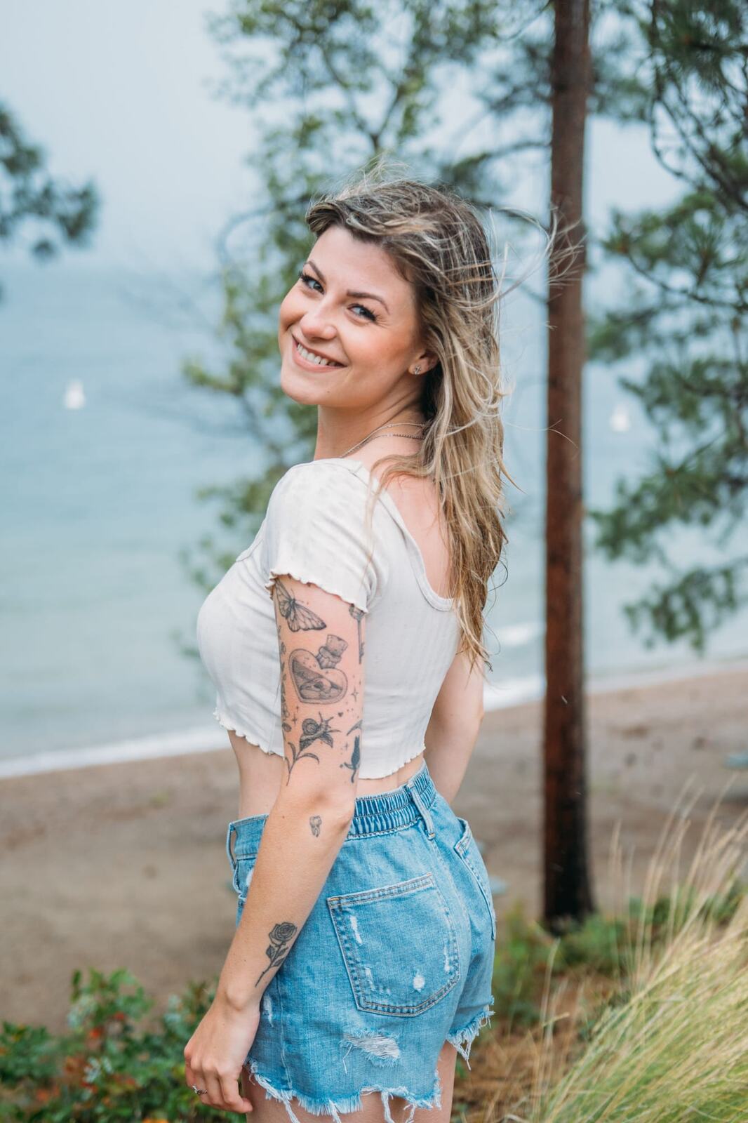 Sophia by the Lake portraits story frame 8: A multi-outfit Okanagan location session with water, trees, shoreline, denim and red swimwear woven into a summer portrait story.