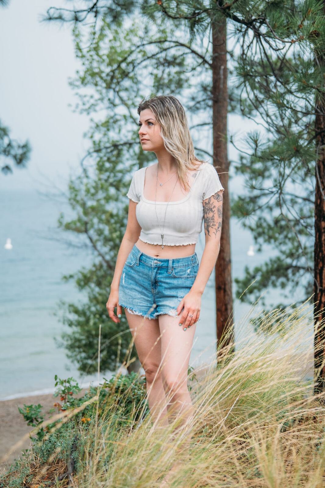 Sophia by the Lake portraits story frame 10: A multi-outfit Okanagan location session with water, trees, shoreline, denim and red swimwear woven into a summer portrait story.
