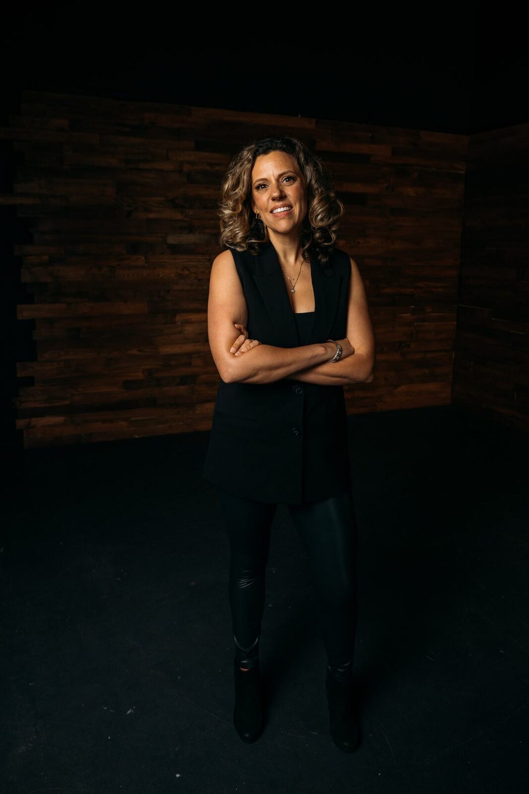 Trisha Miltimore corporate story frame 11: Personal-brand portraits for Trisha Miltimore in Kelowna, moving from clean business profile images into darker wood-wall portraits with black wardrobe and confident brand range..