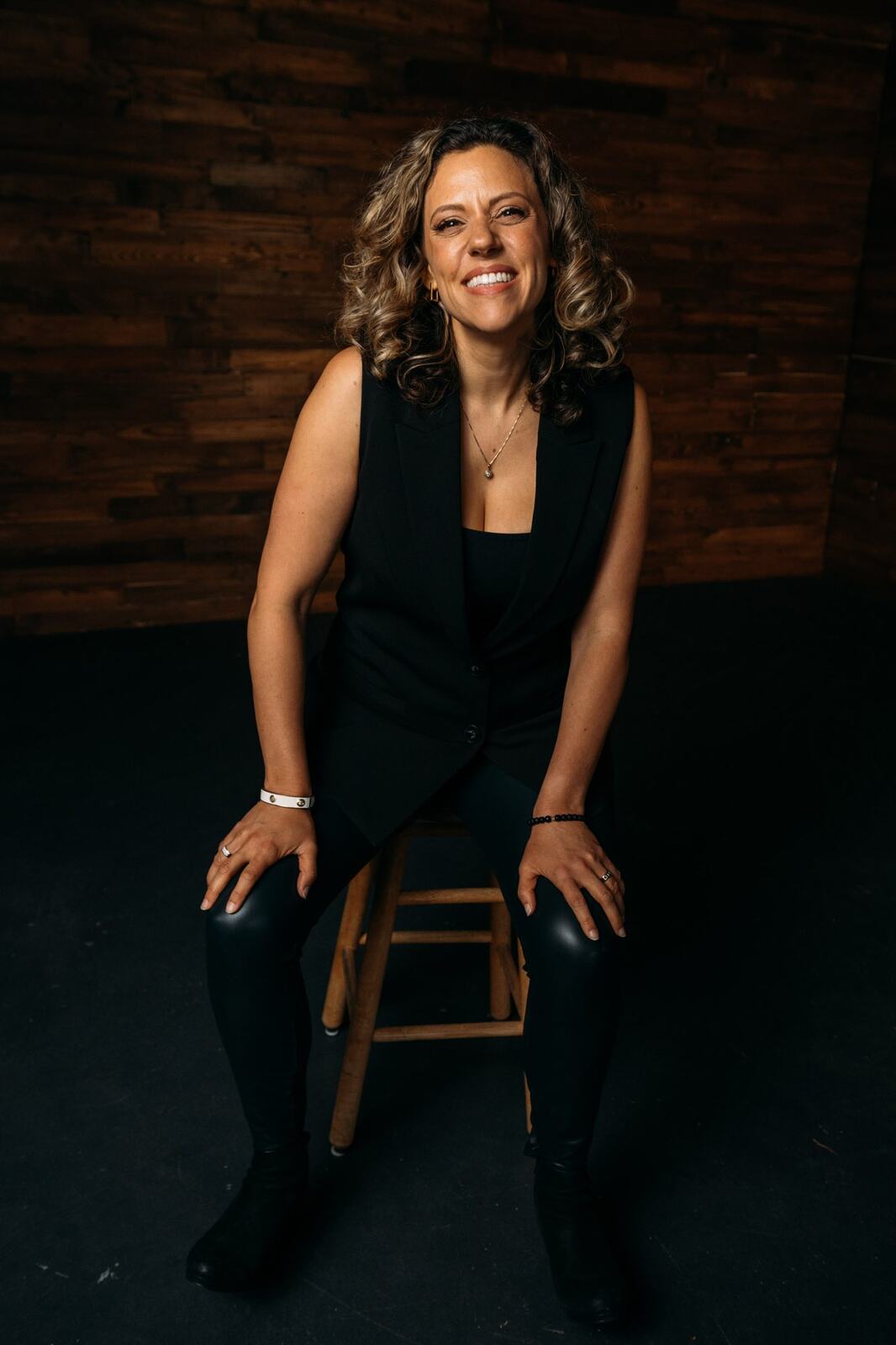 Trisha Miltimore corporate story frame 12: Personal-brand portraits for Trisha Miltimore in Kelowna, moving from clean business profile images into darker wood-wall portraits with black wardrobe and confident brand range..