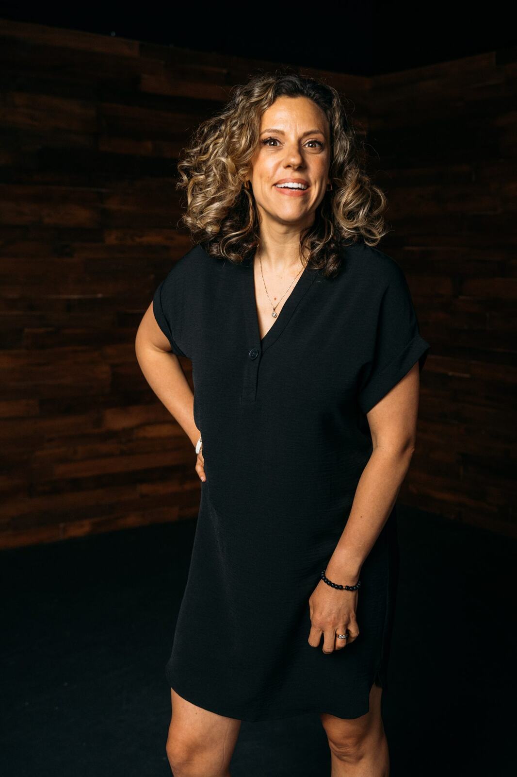Trisha Miltimore corporate story frame 17: Personal-brand portraits for Trisha Miltimore in Kelowna, moving from clean business profile images into darker wood-wall portraits with black wardrobe and confident brand range..