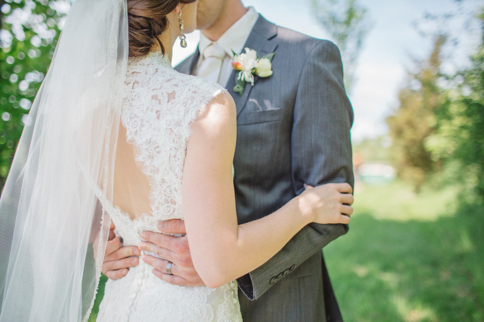 Close wedding portrait with veil, hands and quiet summer light