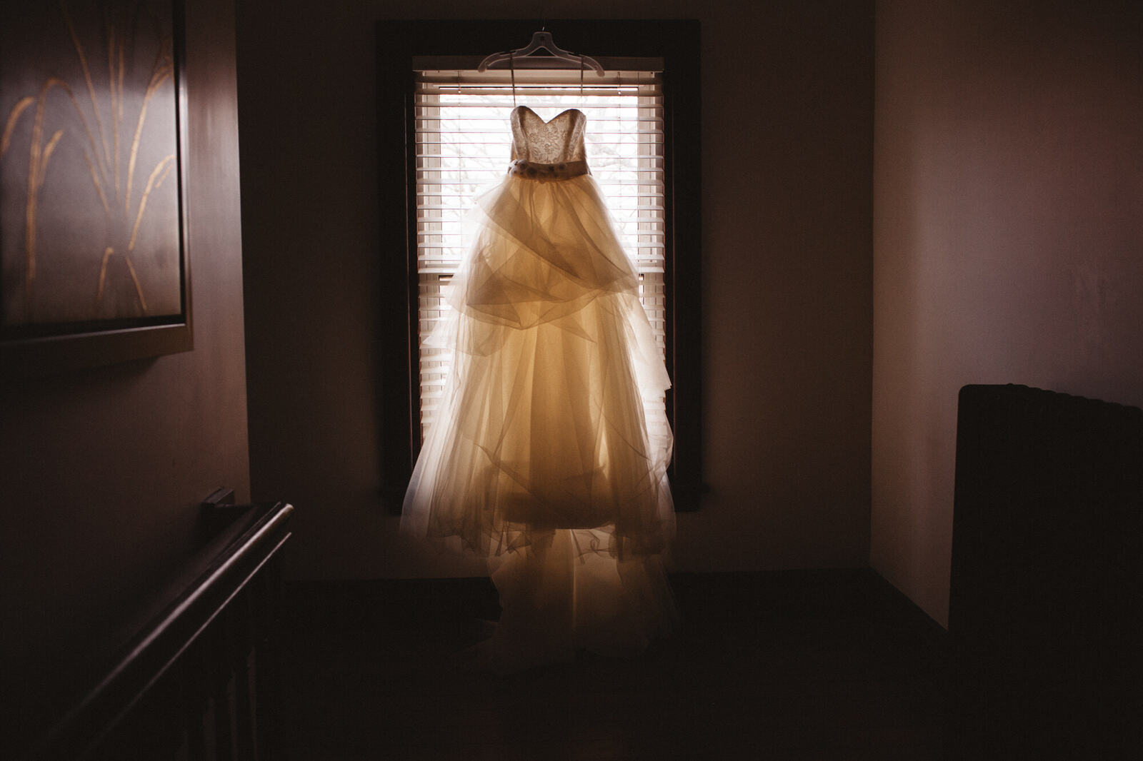 Wedding dress hanging in a dark room window