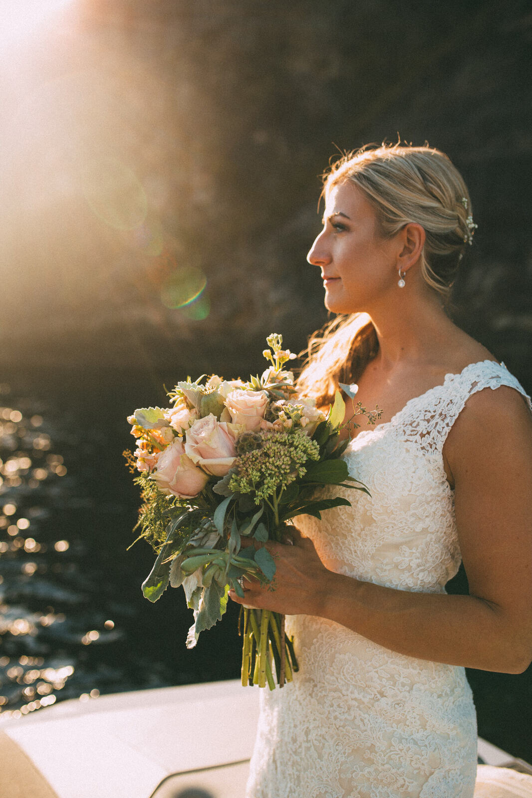Bride holding her bouquet in golden water light